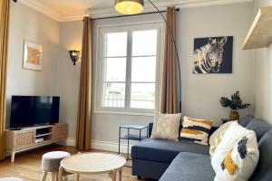 ein Wohnzimmer mit einem blauen Sofa und einem TV in der Unterkunft Suites Rive Gauche - Région Fontainebleau - Chez Victor in Melun