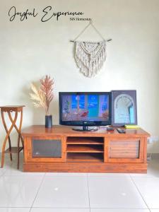 a television on a wooden entertainment center in a living room at GreeneryHome 1-4pax Trefoil Studio Setia Alam in Shah Alam