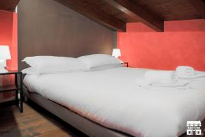 1 dormitorio con cama blanca y pared roja en THE LOFT by Design Studio, en Bellano