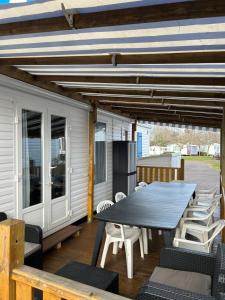 a patio with a table and chairs on a deck at Mobilhome camping les petits écureuils 4 étoiles Biscarrosse in Biscarrosse