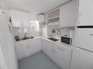 una cocina blanca con armarios blancos y fregadero en Marino II REA-MA207, en Alcossebre