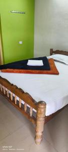 a wooden bed in a room with a green wall at Madhuvana Guest House in Madikeri