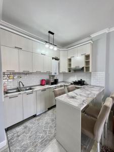 a kitchen with white cabinets and a marble counter top at Keruen Saray Apartments в центре города in Türkistan