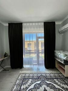 a bedroom with a large window with black curtains at Keruen Saray Apartments в центре города in Türkistan