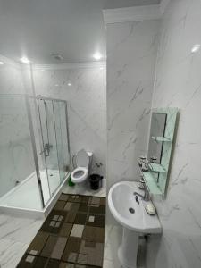 a bathroom with a sink and a shower and a toilet at Keruen Saray Apartments в центре города in Türkistan