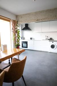eine Küche mit weißen Schränken sowie einem Tisch und Stühlen in der Unterkunft Furnished - Bright, Modern apartment in Brussels, 15 minutes walk from the Atomium in Brüssel