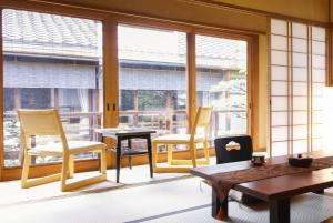Habitación con sillas, mesa y ventanas. en Ryokan Sanga en Kioto