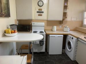 una cocina con electrodomésticos blancos y una mesa con un bol de fruta en CENTRAL LOCATION! Double Bedroom 2 Mins Walk from Battersea Power underground Station! en Londres