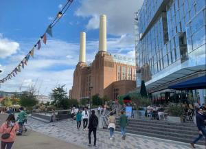 a group of people walking in front of a factory at CENTRAL LOCATION! Double Bedroom 2 Mins Walk from Battersea Power underground Station! in London