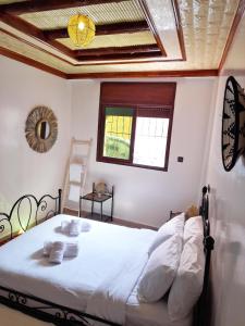 a bedroom with a bed with white sheets and a window at Olympe Surf & Yoga in Tamraght Ouzdar