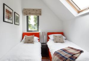 twee bedden in een kamer met witte muren en ramen bij Stalker's Lodge in Perth