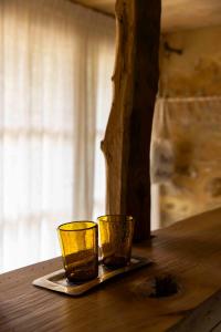 two yellow glasses sitting on top of a wooden table at Maison Bellamant in Alan