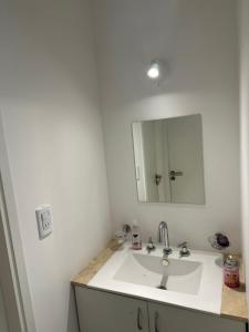 y baño con lavabo blanco y espejo. en Departamento para 4 personas con excelente ubicacion Parking privado en Mendoza