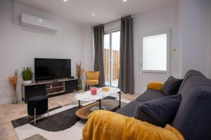 ein Wohnzimmer mit einem blauen Sofa und einem TV in der Unterkunft Apparts Gambetta in Libourne