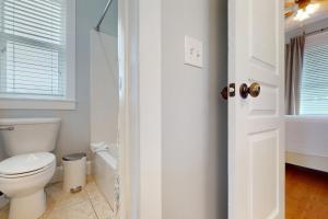 a white bathroom with a toilet and a window at Panhandle Luxury Beach House in Panama City Beach