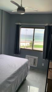 a bedroom with a bed and a window with a view of the beach at Praia do forte II in Cabo Frio