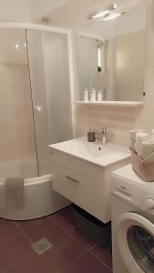 een witte badkamer met een wastafel en een wasmachine bij Relax in Preko
