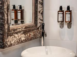 La salle de bains est pourvue d'un miroir et d'un lavabo. dans l'établissement Grand Hotel Lafayette, à Paris