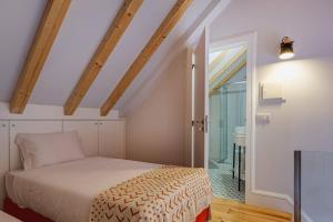 ein Schlafzimmer mit einem Bett und einer Tür zu einem Bad in der Unterkunft Cais das Pedras Duplex by Cozy Stay in Porto