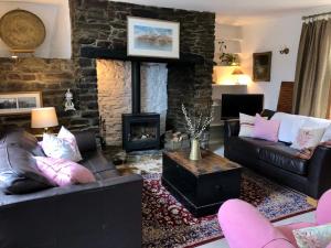Una sala de estar con dos sofás y una chimenea de piedra. en Lake Villa Holiday Cottages, en Holsworthy