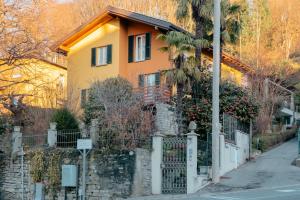A Casa Di Maria في كومو: منزل اصفر وفيه سياج على شارع