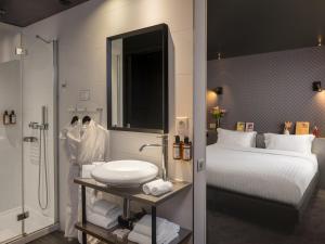 łazienka z łóżkiem, umywalką i prysznicem w obiekcie Grand Hotel Lafayette w Paryżu