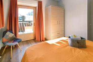 a bedroom with a bed and a chair and a window at Mountain Apartments Livigno in Livigno