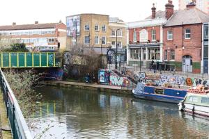 un río con barcos en una ciudad con graffiti en Broadway Market Canal-View Oasis en Londres