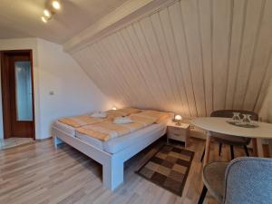 a bed in a room with a table at Cafe & Pension Carmen in Brotterode-Trusetal
