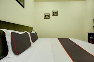 1 dormitorio con 1 cama con almohadas blancas y negras en Ovel Hotel Grand, en Ābādpura