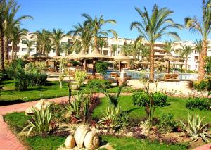 a resort with a garden with palm trees and a pool at Pyramisa Sunset Pearl Apartments in Hurghada