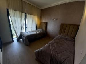 een slaapkamer met 2 bedden en een raam bij Luxe Bord de Mer Appart Prestige in Agadir
