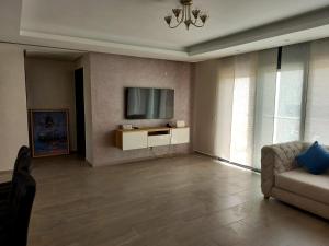 een woonkamer met een bank en een televisie bij Luxe Bord de Mer Appart Prestige in Agadir