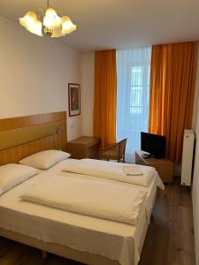 um quarto com uma cama grande e uma televisão em City Hotel Post 11 em Braunau am Inn