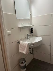 a white bathroom with a sink and a mirror at City Hotel Post 11 in Braunau am Inn