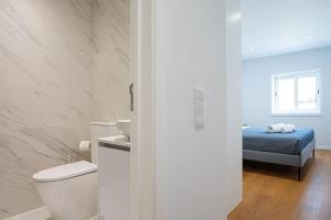 a white bathroom with a toilet and a bed at Charming Beach Retreat by MP in Madalena