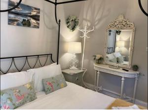 1 dormitorio con cama con espejo y mesa en Storrs Gate House, en Bowness-on-Windermere