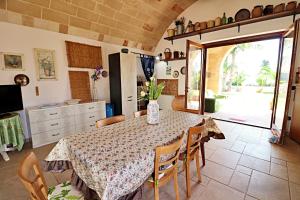 eine Küche mit einem Tisch und Stühlen sowie eine Küche mit einer Tür in der Unterkunft Villa Alida - Con Ampio Giardino E Piscina Privata Nel Salento in Andrano