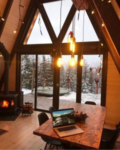 een laptop op een houten tafel in een kamer met een open haard bij The Sunset Cabin будиночок з Чаном in Zhuraky