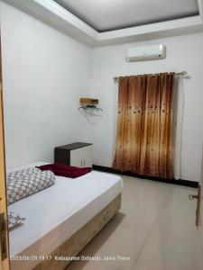 biały pokój z łóżkiem i oknem w obiekcie Homestay Sidoarjo - Comfort w mieście Gedangan
