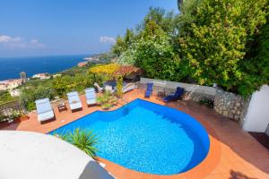 a swimming pool on a patio with chairs and the ocean at YourHome - Villa Mia in Massa Lubrense