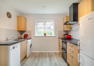 uma cozinha com electrodomésticos brancos e uma janela em Cornfield Bungalow em Haddiscoe