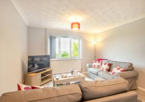 uma sala de estar com um sofá e uma televisão em Cornfield Bungalow em Haddiscoe