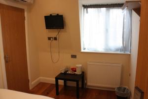 a bedroom with a television on the wall and a table at Hotel Olympia in London