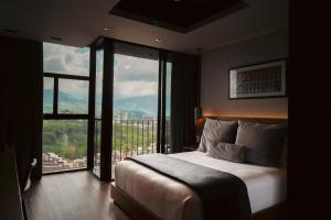 a bedroom with a bed and a large window at Hotel Sexto by Icono in Armenia
