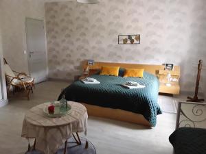 a bedroom with a large bed and a table at Chez Domi Jardin du bourg in Javerlhac-et-la-Chapelle-Saint-Robert