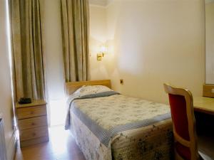 ein kleines Schlafzimmer mit einem Bett und einem Schreibtisch in der Unterkunft The Gresham Hotel in London