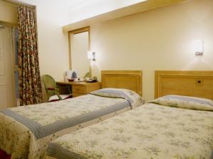 Habitación de hotel con 2 camas y escritorio en The Gresham Hotel en Londres