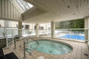 a large swimming pool in a building with a hot tub at Bright 2 bedroom and loft suite in the Wildwood Lodge in Whistler
