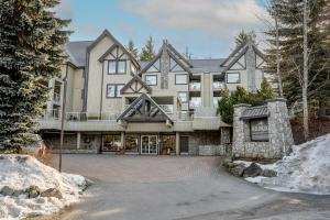a large house with a driveway in front of it at Bright 2 bedroom and loft suite in the Wildwood Lodge in Whistler